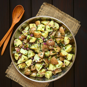 拍照土豆红洋葱和用木勺叉子碗中的草药用自然光照在黑木头上美食二次方图片