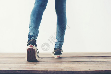 穿蓝色的时髦酷女人脚搭配黑色运动鞋柔软复古色调时髦酷女人脚搭配黑色运动鞋柔和复古色调凉爽的背景图片