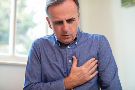 男人鬼脸在家遭受心脏攻击和胸部疼痛的成熟人卫生保健图片