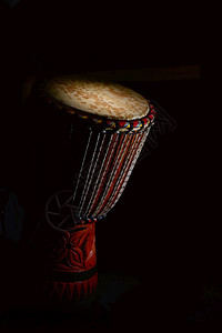 素材非洲鼓Djembe撞击部分在黑色背景上被照亮细节黑色的音乐家设计图片