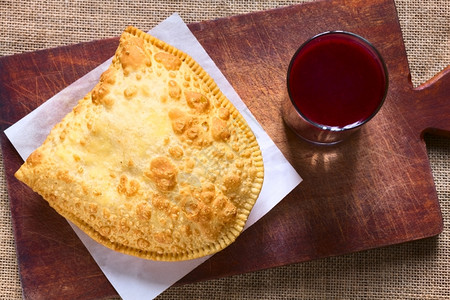 玻璃利维亚传统零食叫做派斯特尔深炸糕饼盛满奶酪的薄饼配有木板上的紫玉米饮料Api与天然光相照小吃传统的背景