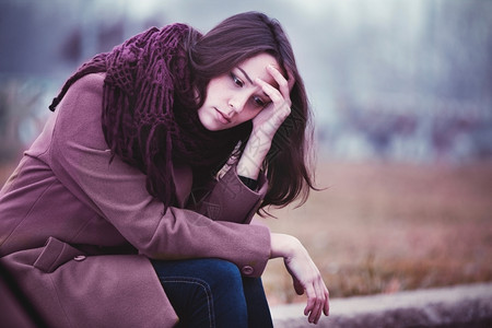 公园令人沮丧的年轻女正坐在萧条中Gloomy秋天的石柱上女士诺维科夫图片