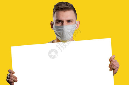 医疗的纸面具戴用口罩的年轻人展示白皮书海报看着黄色背景的相机图片