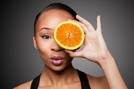 保持美丽的健康快乐黑人亚洲女拿着美味的橘子红番茄果当着眼享受黑色的图片