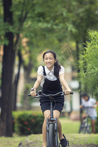 在绿公园骑自行车的亚洲青少年笑脸绿色公园曼谷女士图片