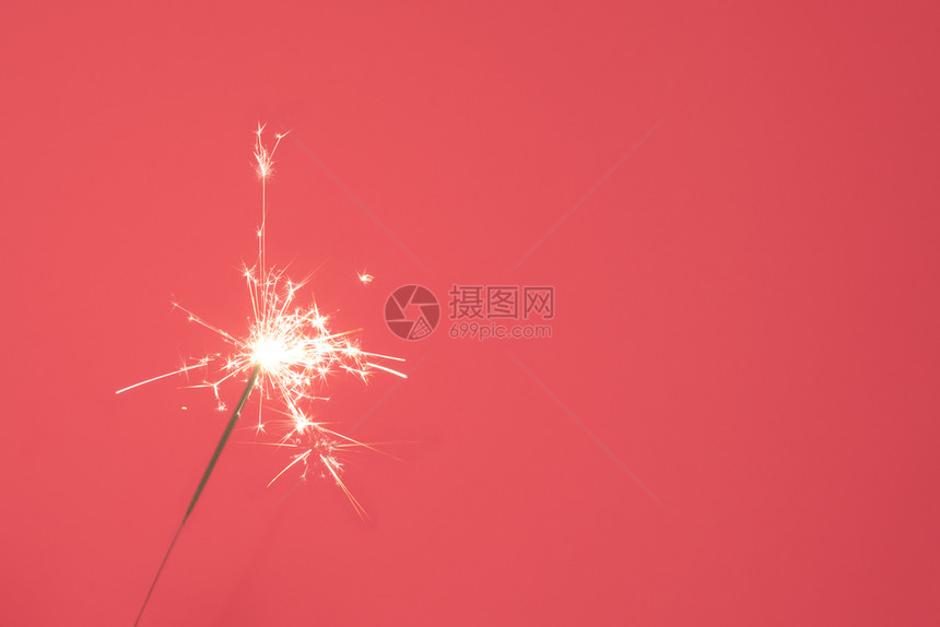 珊瑚前夕发光的在粉红背景上紧贴着明亮燃烧的火花欢乐新年庆祝活动的概念复制空间关闭在粉红背景上闪亮燃烧的火花图片