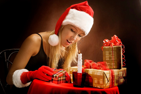 头发穿着圣诞老人服装的年轻女孩看着圣诞礼物年轻的喜悦图片
