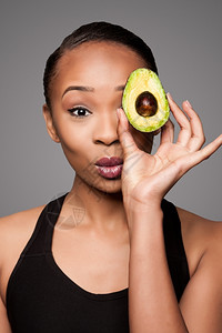 食物维生素黑色的美丽健康快乐黑人亚洲女拿着美味的鳄梨超水果当着眼看图片