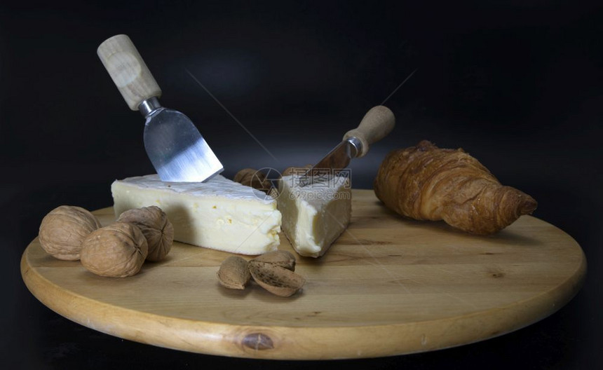 配着法国奶酪的可腐烂木制干酪盘子叫做Brie用刀子和法式羊角面包胡桃和杏仁一种核美味图片