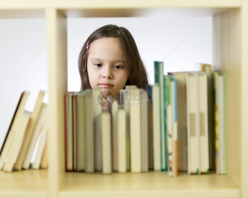 现代的聪明年轻女孩在书架后面的图馆里翻阅本读图片
