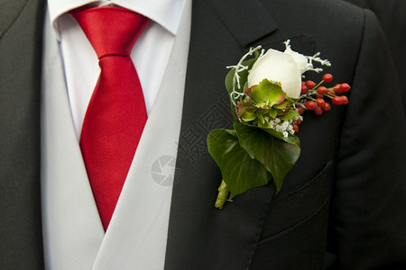 新郎尾衣扣子上的白玫瑰补充了红领带的颜色婚礼棉布尾巴图片