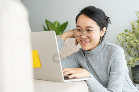 商业在家做笔记本电脑的亚洲女人在沙发工作时笑脸随意的人们图片