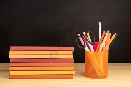 补给品小样木制桌板和背景黑的书本和办公用品架子铅笔图片
