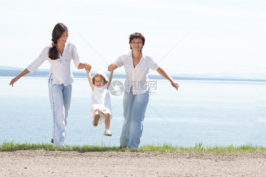 家庭欢乐的微笑母亲和两个Daughtetersr一起在阳光夏日水景台玩随意的快乐图片