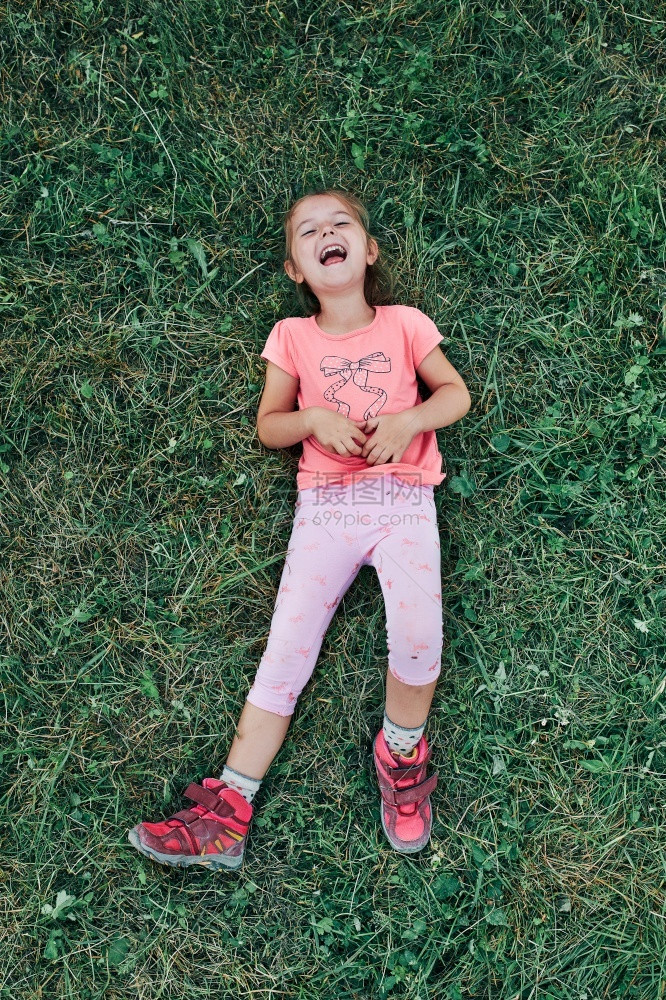 小女孩躺在草地上玩耍享受夏天的假期快乐孩子在周末旅行中田野里玩耍小女孩在度假时草地上玩游戏在暑假旅行中度过夏日积极的请享用愉快图片
