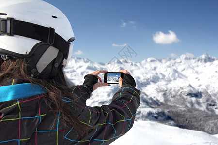 臭鼬运动女孩在手机冬季风景雪下山丘上拍摄照片游客图片