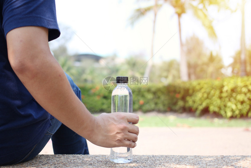干净的喝产品坐在花园里的人旁边放着一瓶饮用水放在花园边上图片