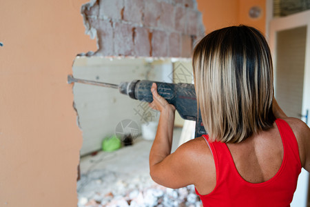 钻头砖妇女背视用充气锤子钻破其公寓的墙壁准备翻新大锤机PHA屋图片