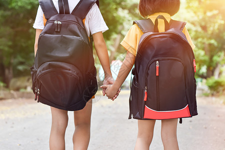 户外快乐的学习回到校两个姐妹生背着包手牵并一起上学的姐妹生教育概念图片