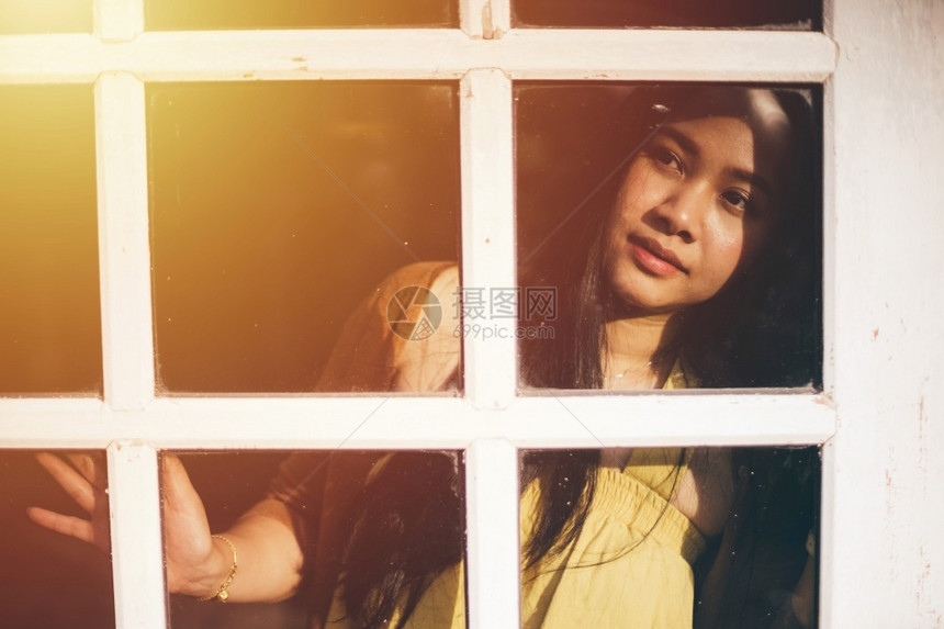 美丽的孤独站在窗户旁看的亚洲女人年轻的图片