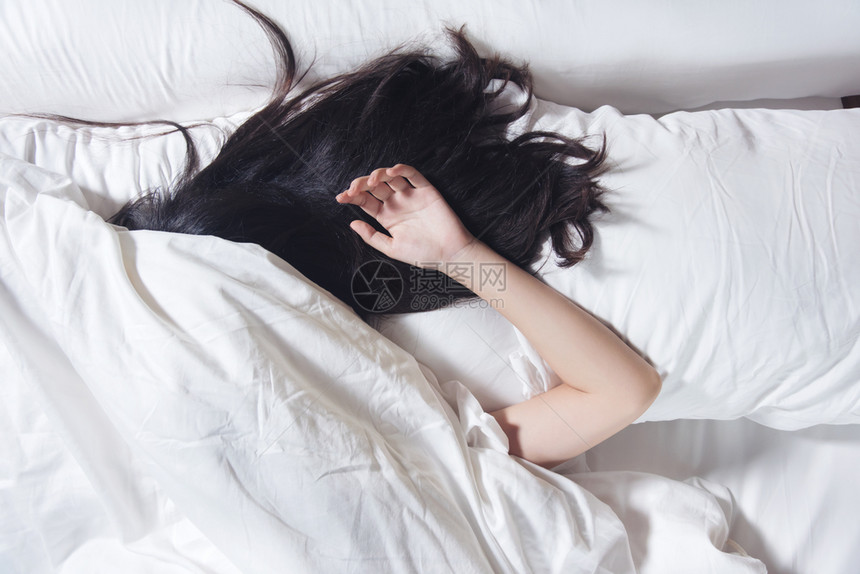 睡在白色枕头和床上的黑发夜醒着女人卧室家们图片