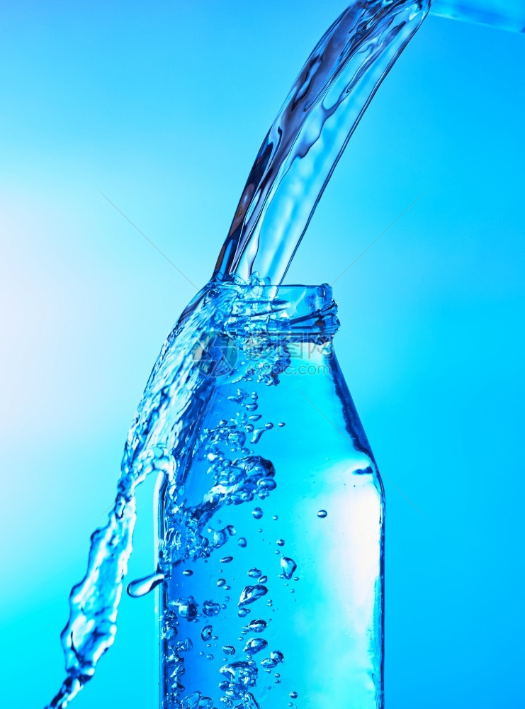将水倒入玻璃中以蓝底为的玻璃杯矿物瓶子透明图片