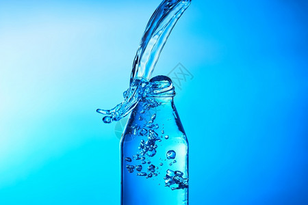 将水倒入玻璃中以蓝底为的玻璃杯瓶子行动进入图片