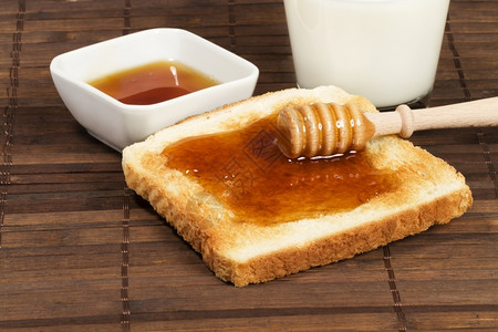 蜂蜜早餐和薄饼在烤面包上加蜂蜜与一杯牛奶和瓶加蜂蜜罐子糖浆甜点木制的图片