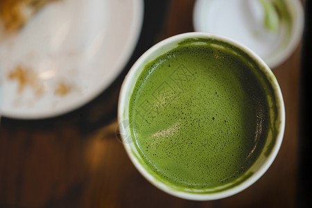 城市的早餐桌上咖啡厅或场景杯中抹茶绿拿铁的特写黑暗背景图片