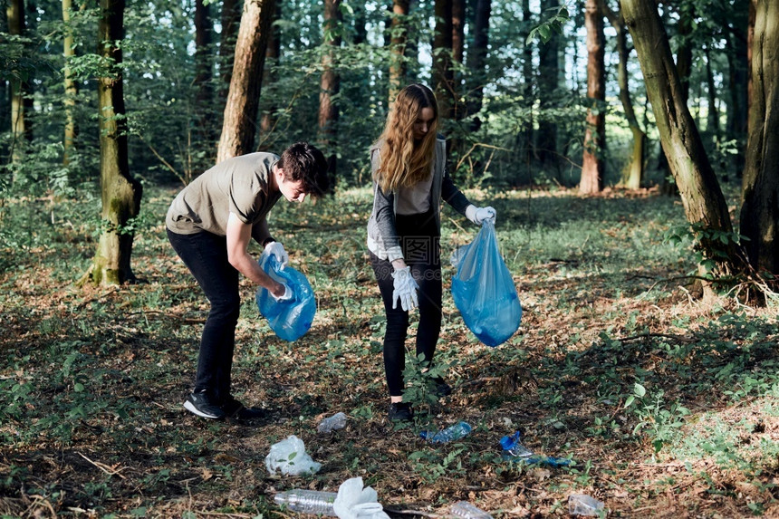 真正的清理森林年轻男女志愿者将塑料垃圾装入袋子塑料污染和过多垃圾的概念环境问题损害对的责任真实人情况在职女士图片