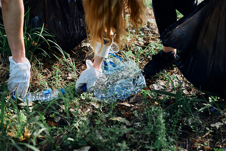 真实塑料孩子清理森林的年轻男女志愿者将塑料垃圾装入袋子塑料污染和过多垃圾的概念环境问题损害对的责任真实人情况正女孩背景