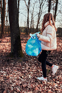孩子清理森林的年轻女子志愿者将塑料垃圾装入袋子塑料污染和过多垃圾的概念环境问题损害对的责任真实人情况为了女士背景图片