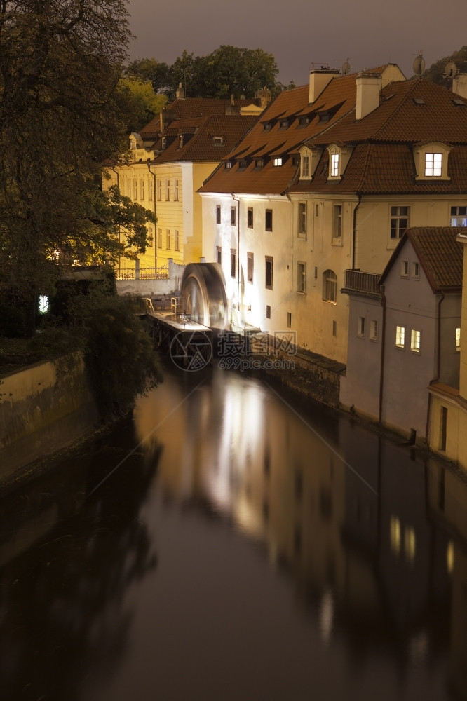 城市从Charles桥上看到的布拉格一条运河的夜景最后一个老式水轮在慢转动夜晚的光亮中造成模糊不清车轮创造图片