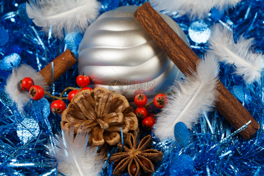松果肉桂棒恒星羽毛和银色的黄瓜放在蓝色锡子上作为圣诞节的装饰品为了明亮的戳图片