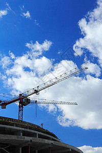 建筑工地面对蓝色天空和云层的起重机框架商业行图片