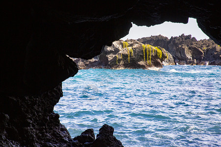 探洞者冒险蓝色的探洞海面穴在黑暗的岩石外向着蓝梅上的开阔背景