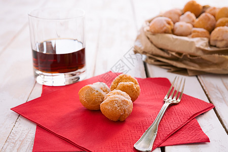 酒红色卡素材背光甜的Castagnole典型的意大利嘉年华糖果红餐巾纸和一杯LiqueurCastagnole典型的意大利嘉年华甜传统背景