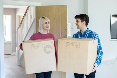 抵押移动盒子年轻夫妇在搬家日携带箱子进新家高清图片