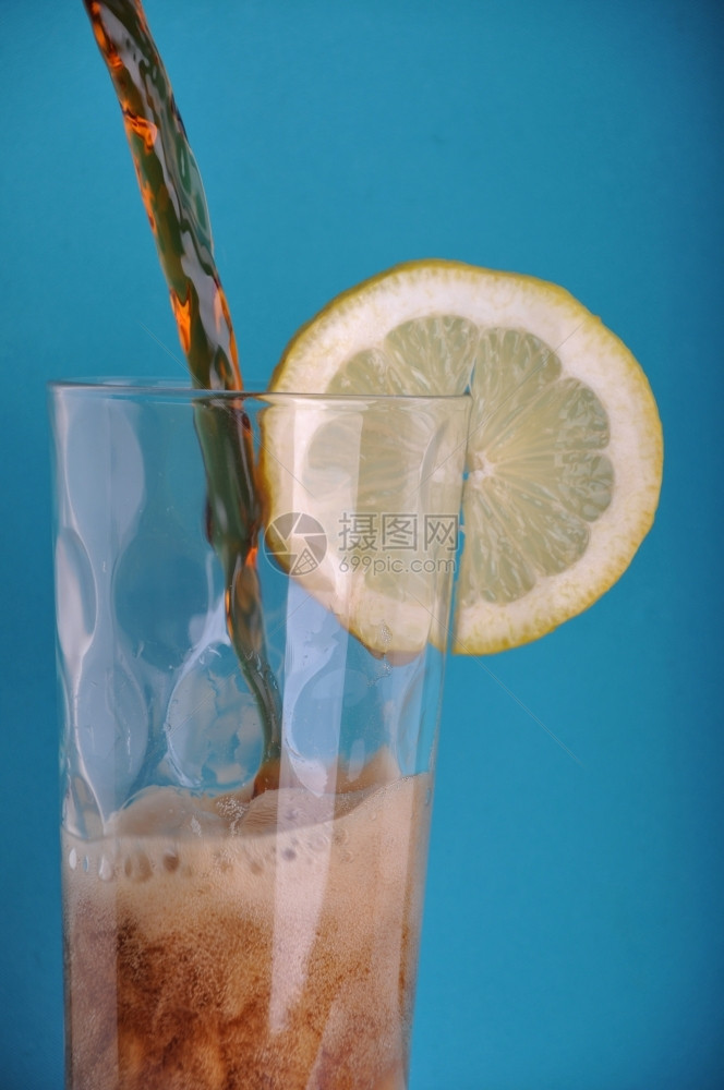 不含酒精的将苏打水倒入杯子有柠檬片蓝色背景寒冷的降低图片