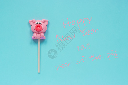 有趣的粉红猪棒糖和英文本新年快乐蓝色背景的猪年顶视图概念贺卡猪年棒糖和文本新年快乐的明信片最佳背景图片