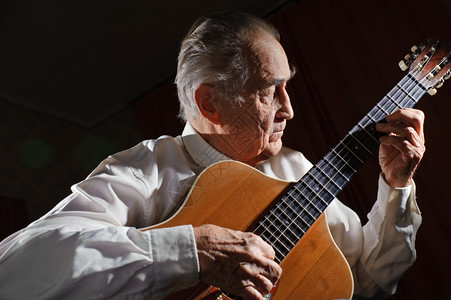 乐器手指闲暇一个穿白衬衫的老人弹着声音吉他黑暗背景图片