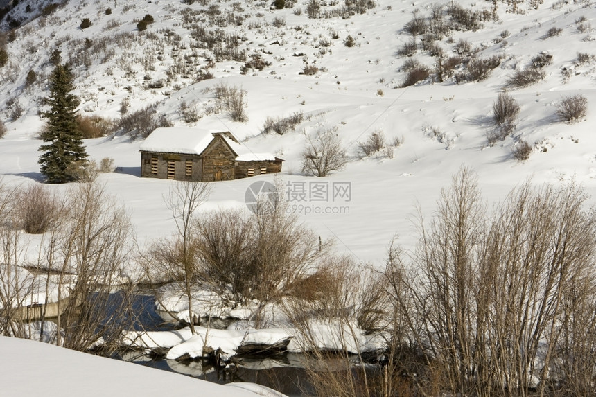 团结的靠近科罗拉多州阿斯彭附近的农村地区一个小谷仓里有全被雪完覆盖在前景中一小条溪流在运行图片