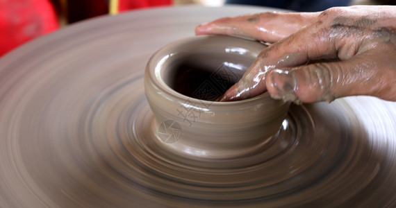 亚洲人波特形式握紧手在陶器轮上工作图片