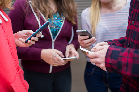 娱乐信息电话一群青少年在手机上分享短信图片