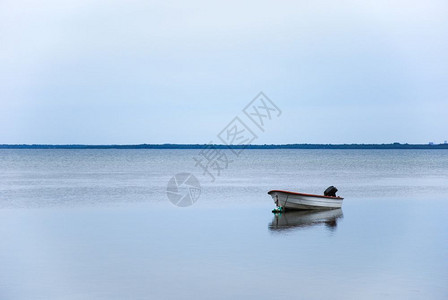 蓝色的海单小船在平静的水中反射湖图片