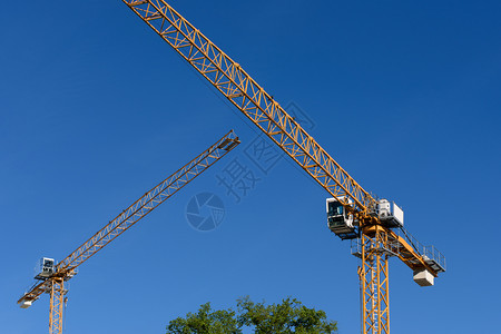 工作建筑学机械的两台蓝色天空背景的通用建筑起重机背景图片