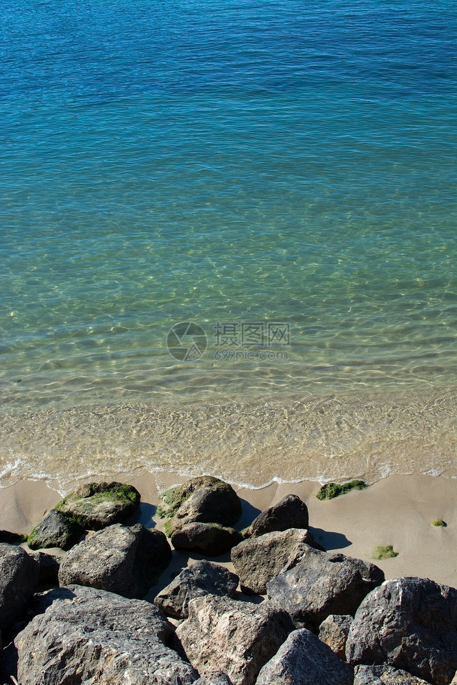 天海滨水中的岩礁和浅沙在阳光明媚的下午关闭在马洛卡西班牙岩礁和绿大洋水中的浅沙上地海图片