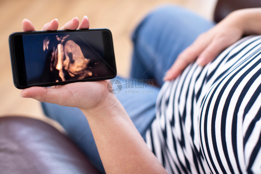 孕妇在3D图像上看婴儿手机照片的详情家水平女士图片