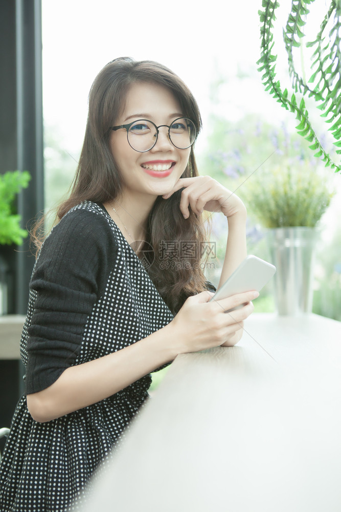 美丽的年轻亚洲女手拿着智能机带牙的笑快乐情感女士放松在线的图片