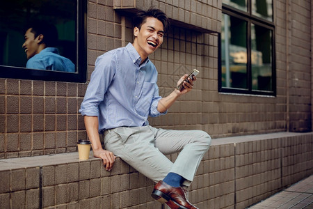 技术专业的在城市使用移动电话微笑的年轻亚洲商人看着相机摄影年轻的图片